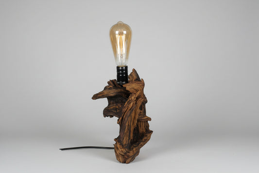 Driftwood lamp with an exposed bulb on a grey background
