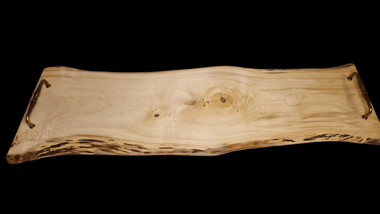 Top view of a long 90cm maple wood live edge serving board with vintage brass handles on a neutral background