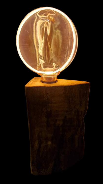 Front view of a handcrafted triangular Ash wood lamp base with a large glowing circular Edison bulb.
