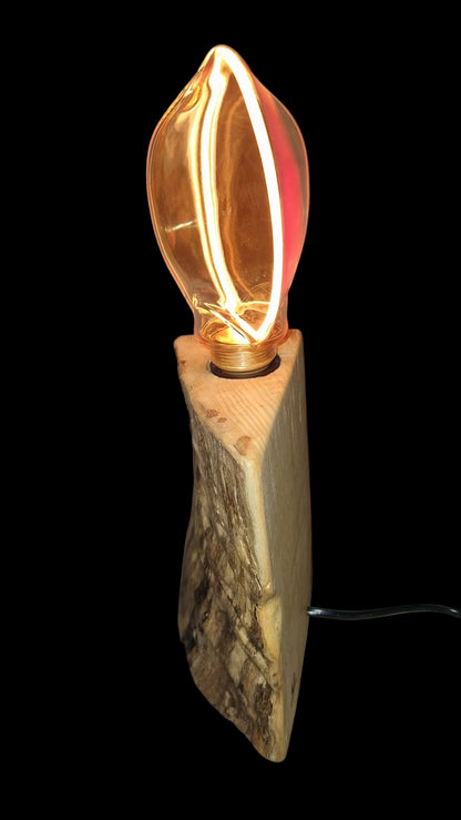 Side view of a handcrafted triangular Ash wood lamp base with a large glowing circular Edison bulb.