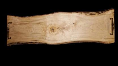 Top view of a long 90cm maple wood live edge serving board with vintage brass handles on a neutral background